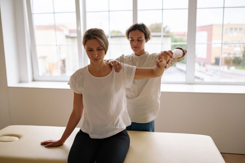 Två personer gör en axel- och armstretch på en behandlingsbänk